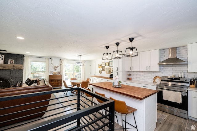 2127 E 5950 N, Liberty, UT 84310 - kitchen with stainless steel electric stove, wall chimney exhaust hood, butcher block countertops, open floor plan, and white cabinetry
