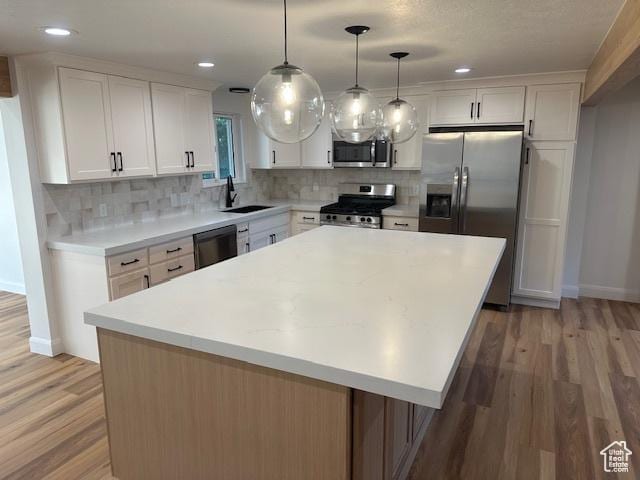 1456 E 5935 S, Murray, UT 84121 - kitchen featuring stainless steel appliances, white cabinets, light wood-style flooring, tasteful backsplash, and a center island