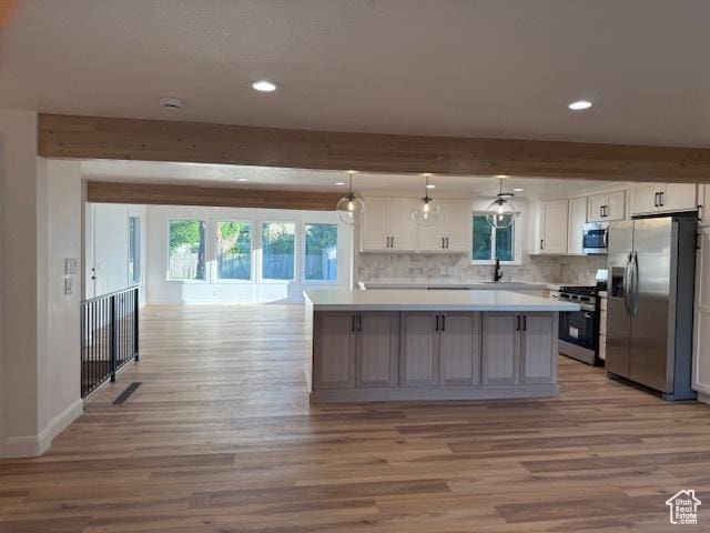 1456 E 5935 S, Murray, UT 84121 - kitchen featuring stainless steel appliances, beam ceiling, light wood-style flooring, a kitchen island, and light countertops