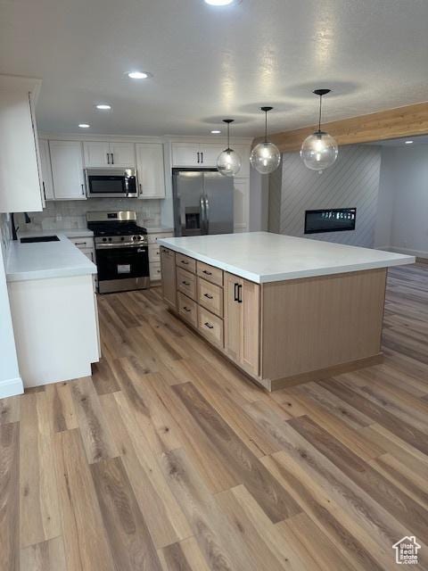 1456 E 5935 S, Murray, UT 84121 - kitchen with appliances with stainless steel finishes, a center island, light wood-style floors, decorative backsplash, and recessed lighting