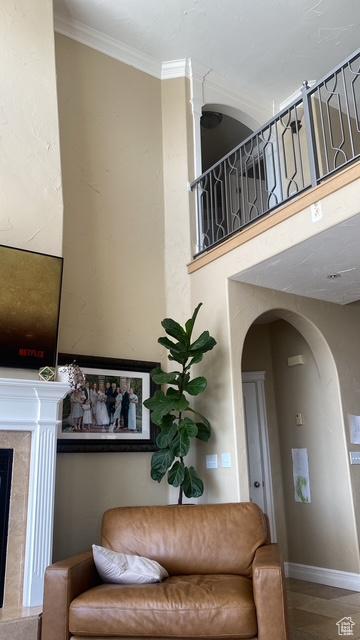 9061 N Canyon Dr, Cedar Hills, UT 84062 - living area with arched walkways, ornamental molding, a high end fireplace, wood finished floors, and a towering ceiling
