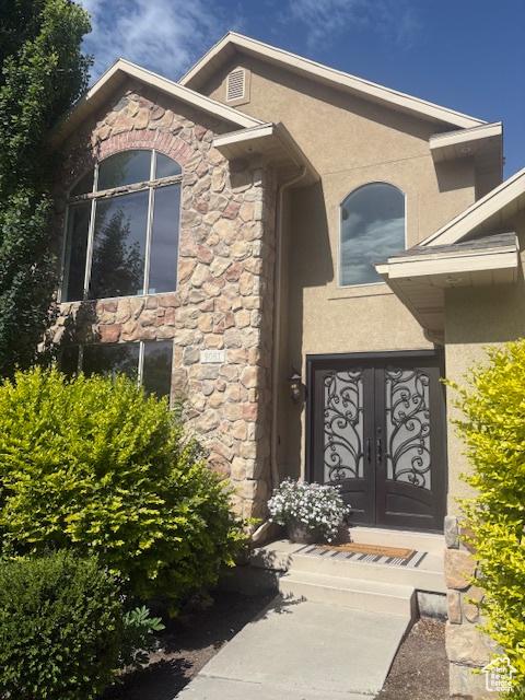 9061 N Canyon Dr, Cedar Hills, UT 84062 - view of exterior entry featuring stone siding, stucco siding, and french doors