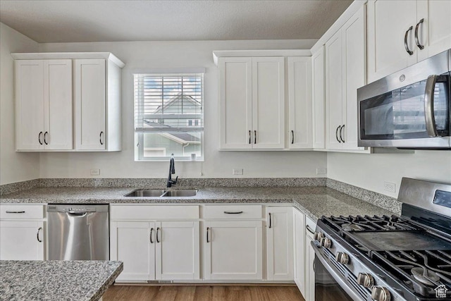 5239 W Mellow Way S, Jordan, UT 84009 - kitchen with stainless steel appliances, white cabinets, light wood-type flooring, and light stone countertops