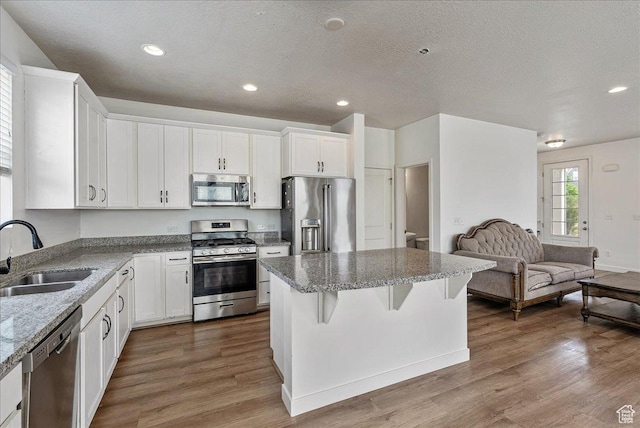 5239 W Mellow Way S, Jordan, UT 84009 - kitchen with stainless steel appliances, a kitchen island, dark wood finished floors, open floor plan, and white cabinets