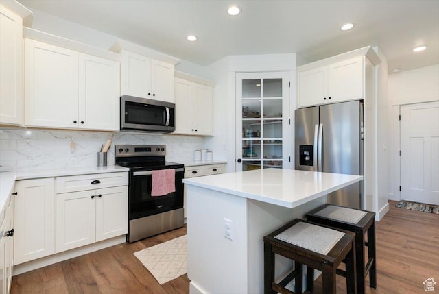 165 N 300 W, Preston, ID 83263 - kitchen with appliances with stainless steel finishes, a kitchen breakfast bar, dark wood-type flooring, white cabinetry, and recessed lighting