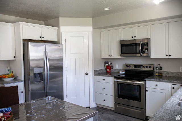 122 N 1325 W, Springville, UT 84663 - kitchen featuring appliances with stainless steel finishes, white cabinetry, dark wood-type flooring, a textured ceiling, and dark stone countertops