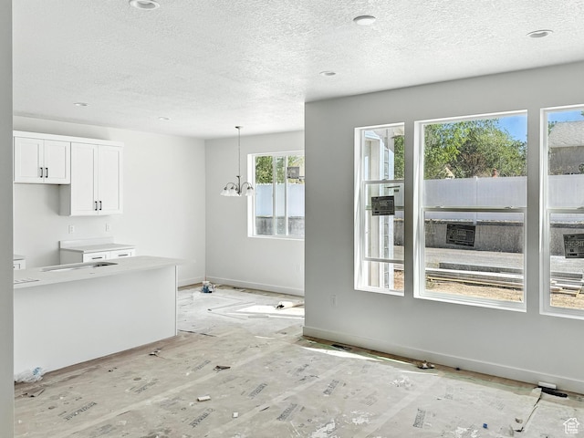 8239 W Joshua Tree Ln, Magna, UT 84044 - kitchen with a textured ceiling, white cabinetry, decorative light fixtures, and a chandelier