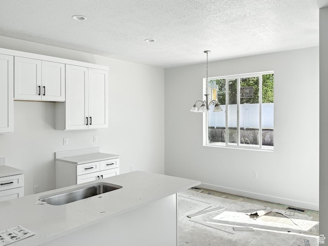 8239 W Joshua Tree Ln, Magna, UT 84044 - kitchen featuring a textured ceiling, white cabinetry, light countertops, and pendant lighting