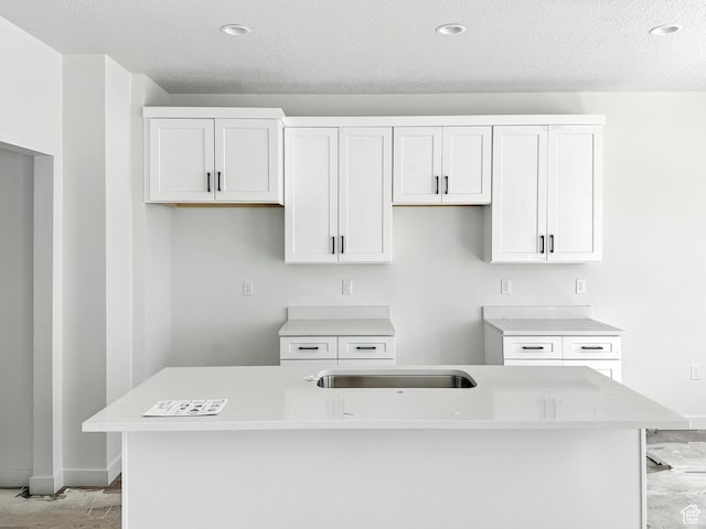 8239 W Joshua Tree Ln, Magna, UT 84044 - kitchen with a kitchen island with sink, a textured ceiling, white cabinets, light countertops, and recessed lighting