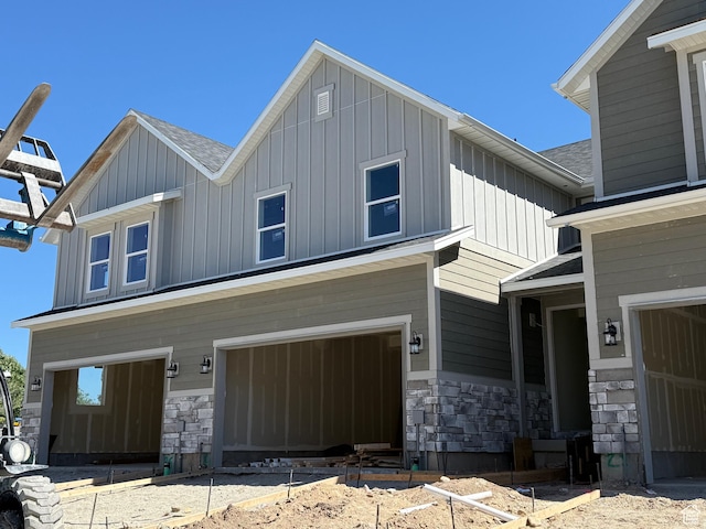 8239 W Joshua Tree Ln, Magna, UT 84044 - view of front of house featuring board and batten siding, stone siding, a garage, and a shingled roof