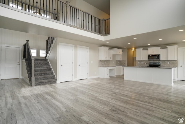 3045 S 2275 W, West Haven, UT 84401 - unfurnished living room featuring a towering ceiling, light wood-style flooring, stairway, and recessed lighting