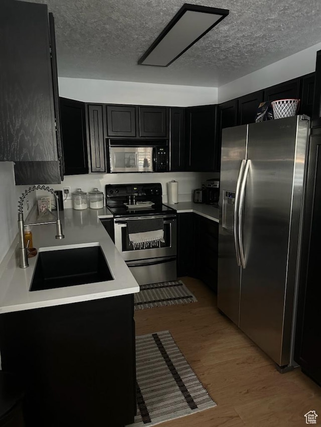 12228 S Madison View Dr, Riverton, UT 84065 - kitchen with stainless steel appliances, dark cabinets, a textured ceiling, light wood finished floors, and light countertops