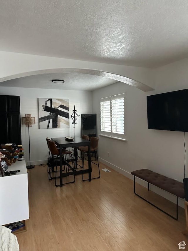12228 S Madison View Dr, Riverton, UT 84065 - dining room featuring a textured ceiling, light wood-style flooring, and arched walkways