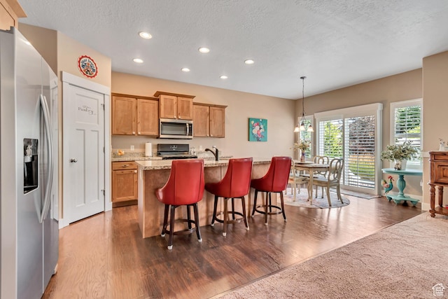 5319 W Elsmere Ln S, Herriman, UT 84096 - kitchen featuring stainless steel appliances, recessed lighting, a textured ceiling, dark wood finished floors, and a kitchen island with sink