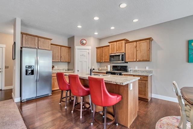 5319 W Elsmere Ln S, Herriman, UT 84096 - kitchen with stainless steel appliances, dark wood finished floors, light countertops, a kitchen island with sink, and recessed lighting
