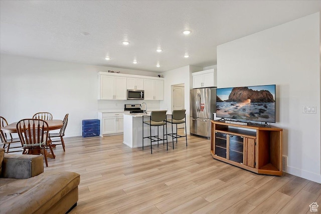 3270 N 3325 W Unit 386B, Plain City, UT 84404 - kitchen with appliances with stainless steel finishes, a kitchen bar, light wood finished floors, recessed lighting, and white cabinets