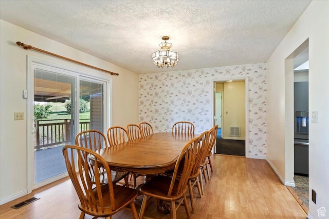 484 E 3450 N, North Ogden, UT 84414 - dining space with light wood-type flooring, a chandelier, a textured ceiling, and wallpapered walls