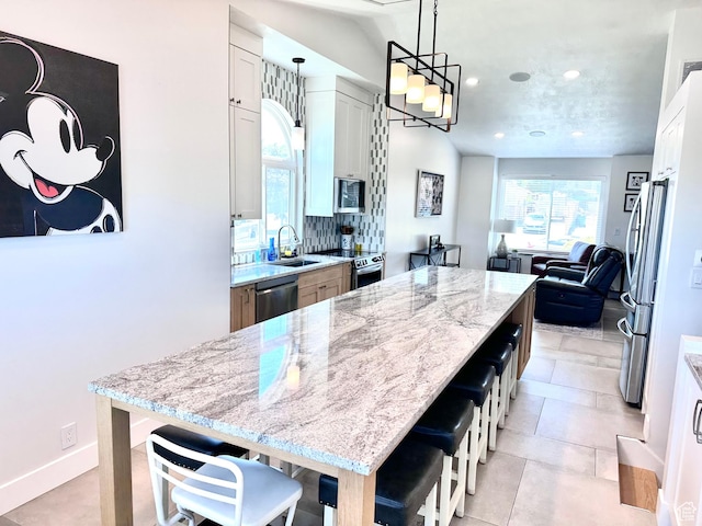 4086 W Wind River Dr, West Jordan, UT 84088 - kitchen with light stone counters, a center island, appliances with stainless steel finishes, recessed lighting, and decorative light fixtures