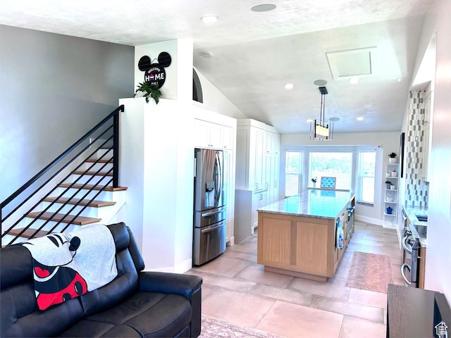 4086 W Wind River Dr, West Jordan, UT 84088 - kitchen with appliances with stainless steel finishes, light stone counters, vaulted ceiling, a kitchen island, and white cabinetry