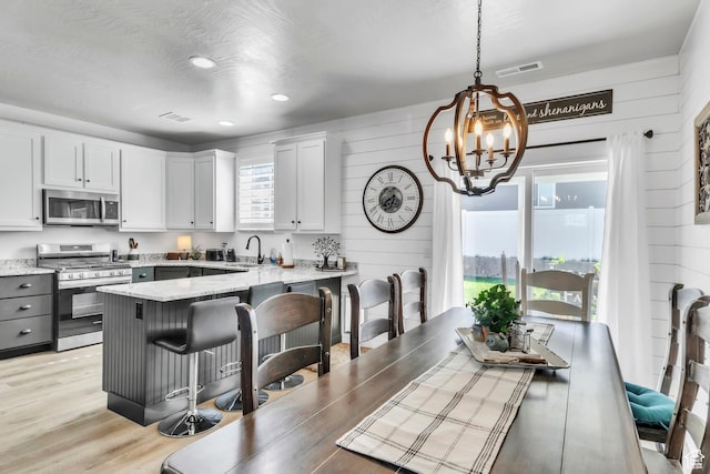 1188 N 100 E, Nephi, UT 84648 - kitchen with appliances with stainless steel finishes, a chandelier, wooden walls, light stone counters, and a kitchen bar