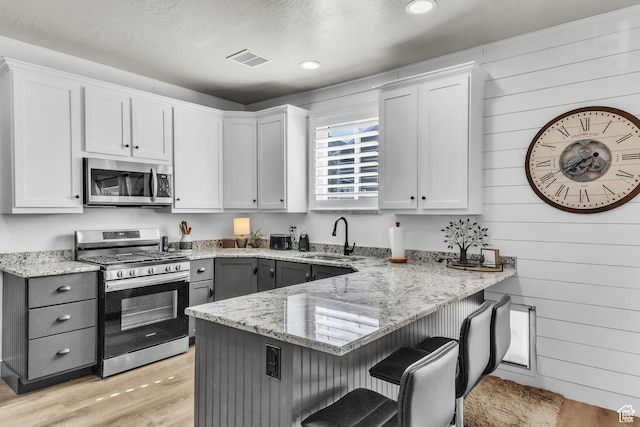 1188 N 100 E, Nephi, UT 84648 - kitchen featuring appliances with stainless steel finishes, a breakfast bar, light stone counters, a peninsula, and wooden walls