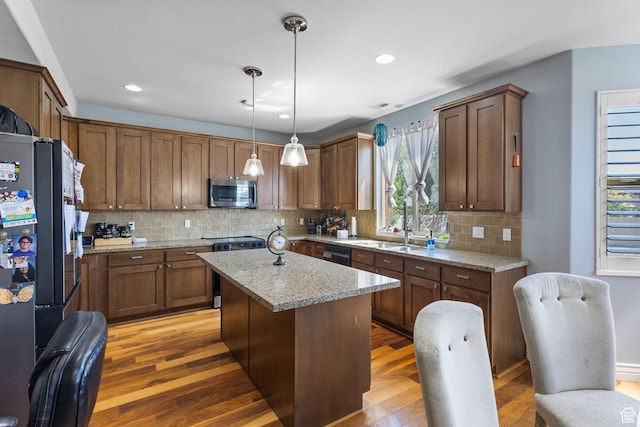 4467 W 5850 S, Hooper, UT 84315 - kitchen with appliances with stainless steel finishes, light wood-style flooring, backsplash, a center island, and decorative light fixtures