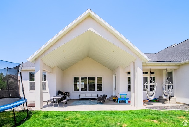 3698 E Butterfield Rd, Eagle Mountain, UT 84005 - rear view of property with a trampoline, a patio area, stucco siding, a yard, and a shingled roof