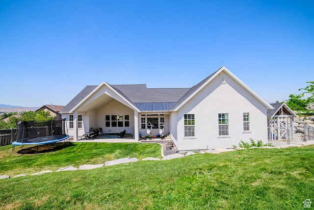 3698 E Butterfield Rd, Eagle Mountain, UT 84005 - back of property with a trampoline, a patio area, and stucco siding