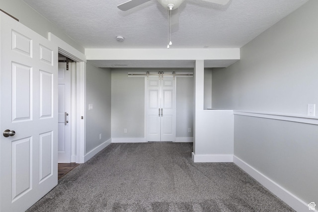 3320 N Plain City Rd W, Plain City, UT 84404 - unfurnished bedroom featuring a barn door, carpet floors, a textured ceiling, a closet, and ceiling fan
