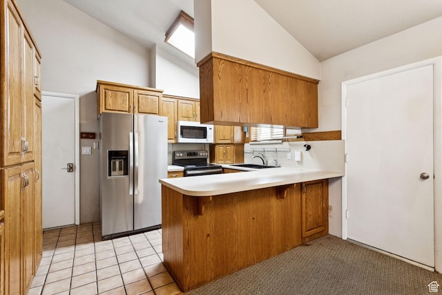 6924 S 2160 W, West Jordan, UT 84084 - kitchen with appliances with stainless steel finishes, brown cabinetry, a peninsula, light countertops, and high vaulted ceiling
