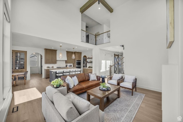 3728 W Chalgrove Rd, Taylor, UT 84401 - living room with arched walkways, light wood-style floors, a towering ceiling, and beamed ceiling