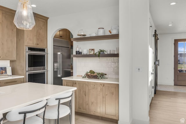 3728 W Chalgrove Rd, Taylor, UT 84401 - kitchen featuring stainless steel appliances, backsplash, light wood-style floors, a barn door, and arched walkways