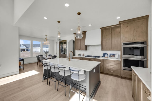 3728 W Chalgrove Rd, Taylor, UT 84401 - kitchen featuring stainless steel double oven, light wood finished floors, a kitchen breakfast bar, backsplash, and recessed lighting