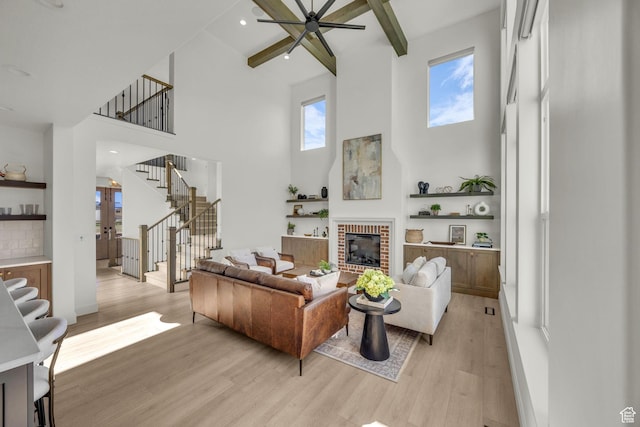 3728 W Chalgrove Rd, Taylor, UT 84401 - living room featuring a towering ceiling, stairs, light wood-type flooring, a ceiling fan, and a brick fireplace