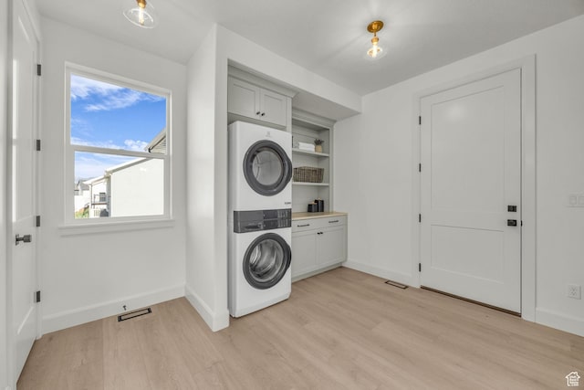 3728 W Chalgrove Rd, Taylor, UT 84401 - laundry area with stacked washing machine and dryer, light wood-style floors, and cabinet space