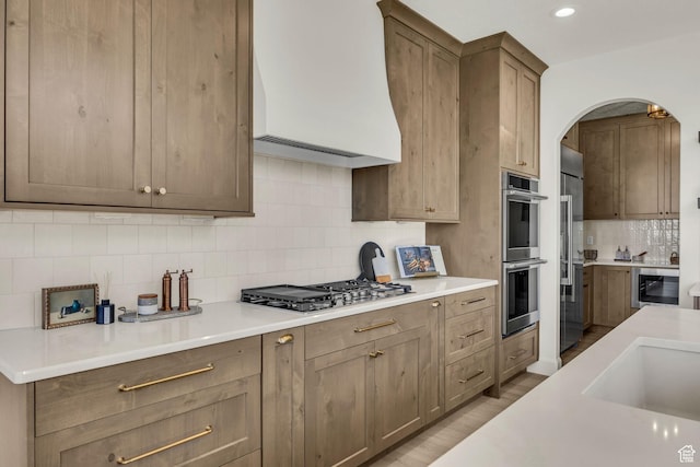 3728 W Chalgrove Rd, Taylor, UT 84401 - kitchen featuring stainless steel appliances, premium range hood, tasteful backsplash, arched walkways, and light countertops
