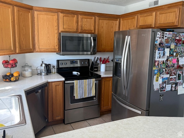 1616 W Vivante Way Unit A3, West Valley City, UT 84119 - kitchen featuring appliances with stainless steel finishes, brown cabinets, light countertops, and light tile patterned flooring