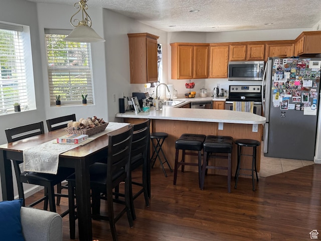 1616 W Vivante Way Unit A3, West Valley City, UT 84119 - kitchen with appliances with stainless steel finishes, a textured ceiling, a peninsula, light countertops, and light wood finished floors