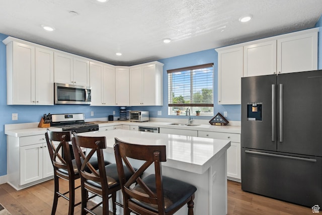 3902 W Pilton Ct, Taylorsville, UT 84129 - kitchen featuring stainless steel appliances, light wood-style floors, light countertops, recessed lighting, and a textured ceiling