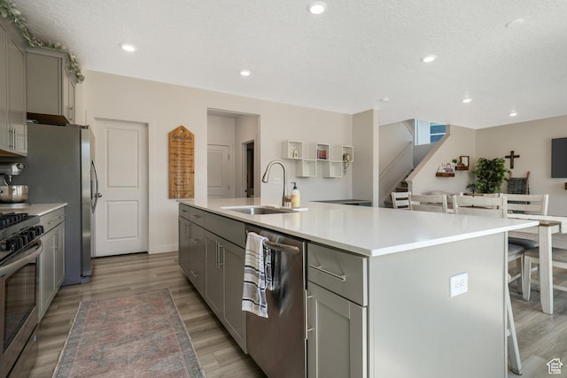 537 W Flora Dr, Saratoga Springs, UT 84045 - kitchen featuring gray cabinetry, appliances with stainless steel finishes, a center island with sink, a kitchen bar, and light countertops