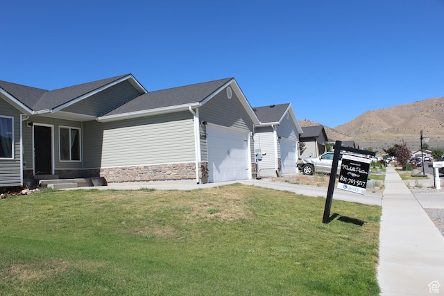 2359 E Prairie Ln, Eagle Mountain, UT 84005 - view of side of property with a garage, a lawn, a mountain view, driveway, and stone siding