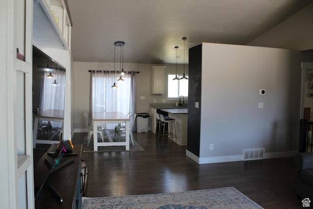 2359 E Prairie Ln, Eagle Mountain, UT 84005 - kitchen with dark wood-style floors, pendant lighting, a breakfast bar area, and white cabinets