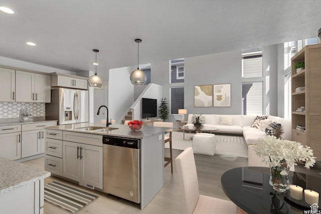 4273 W Watchmen Way, Herriman, UT 84096 - kitchen with stainless steel appliances, open floor plan, tasteful backsplash, hanging light fixtures, and light wood-type flooring