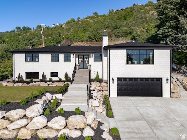 4605 S Ledgemont Dr E, Salt Lake City, UT 84124 - view of front of house with a chimney, an attached garage, concrete driveway, stairway, and brick siding