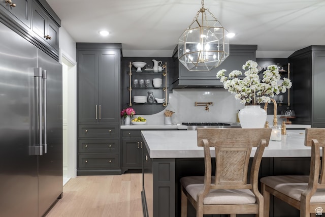 4605 S Ledgemont Dr E, Salt Lake City, UT 84124 - kitchen with stainless steel appliances, light wood finished floors, light countertops, a kitchen breakfast bar, and a chandelier