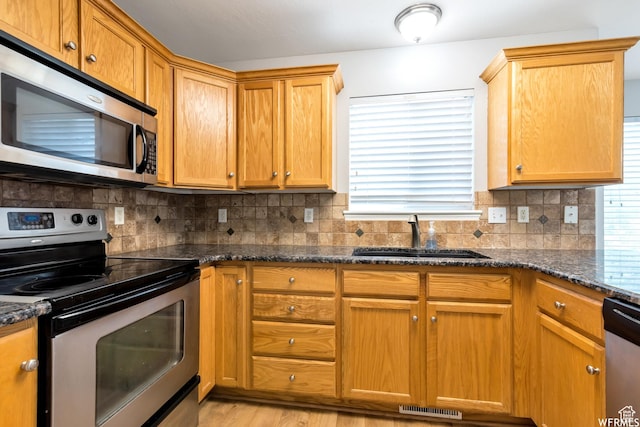 901 S Apple Grove Ln, Pleasant Grove, UT 84062 - kitchen featuring appliances with stainless steel finishes, backsplash, dark stone countertops, and light wood-style floors