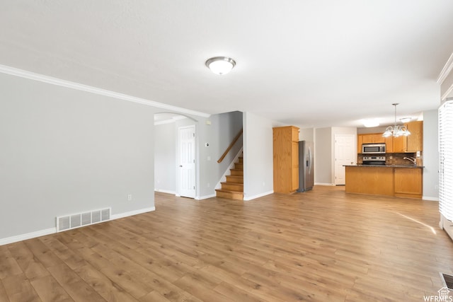 901 S Apple Grove Ln, Pleasant Grove, UT 84062 - unfurnished living room featuring crown molding, arched walkways, stairway, light wood-type flooring, and a chandelier