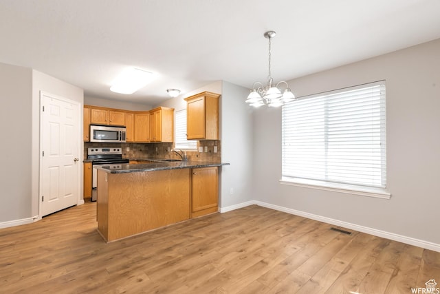 901 S Apple Grove Ln, Pleasant Grove, UT 84062 - kitchen with stainless steel appliances, a chandelier, a peninsula, decorative backsplash, and light wood-type flooring
