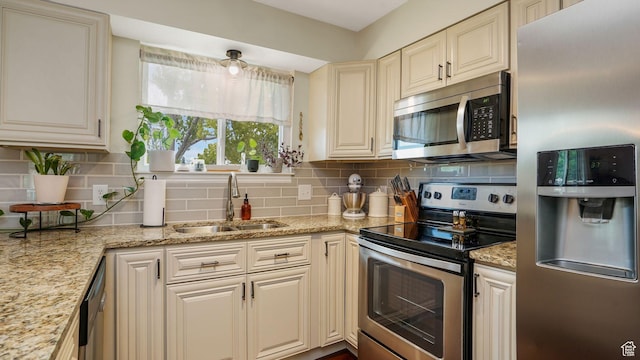 3737 S Washington Dr W, Magna, UT 84044 - kitchen featuring stainless steel appliances, cream cabinetry, decorative backsplash, and light stone countertops