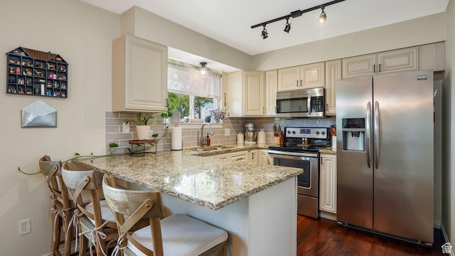 3737 S Washington Dr W, Magna, UT 84044 - kitchen with stainless steel appliances, cream cabinets, a peninsula, light stone countertops, and decorative backsplash